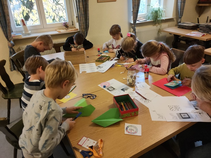 9 Grundschulkinder sitzen an einem Tisch und basteln